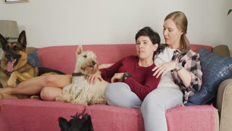 Pareja-De-Lesbianas-Caucásicas-Hablando-Entre-Sí-Sentadas-En-El-Sofá-Con-Su-Perro-En-Casa