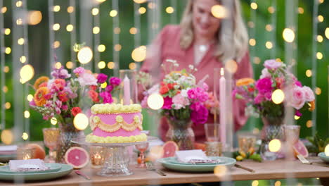 fairy light foreground with beautiful styled wedding party table setting in outdoor garden with pink cake and florals, 4k slow motion