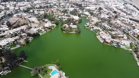 drone shot of a green lake and lake houses on a summer day in the city of lima peru