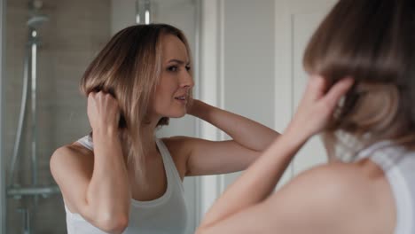 caucasian woman checking hair condition in the bathroom.