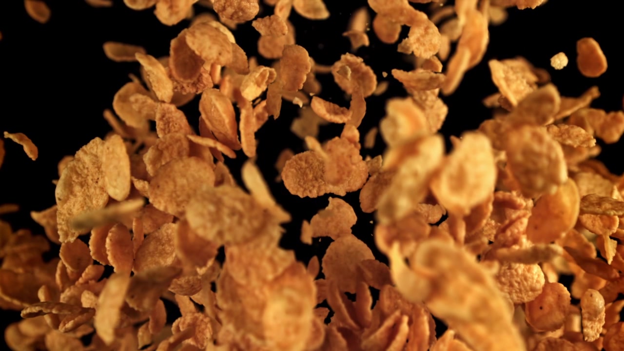 Golden Cornflakes Falling in Slow Motion Against a Black Background