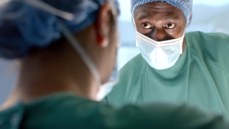 diverse female and male surgeons in masks talking during operation in theatre, slow motion