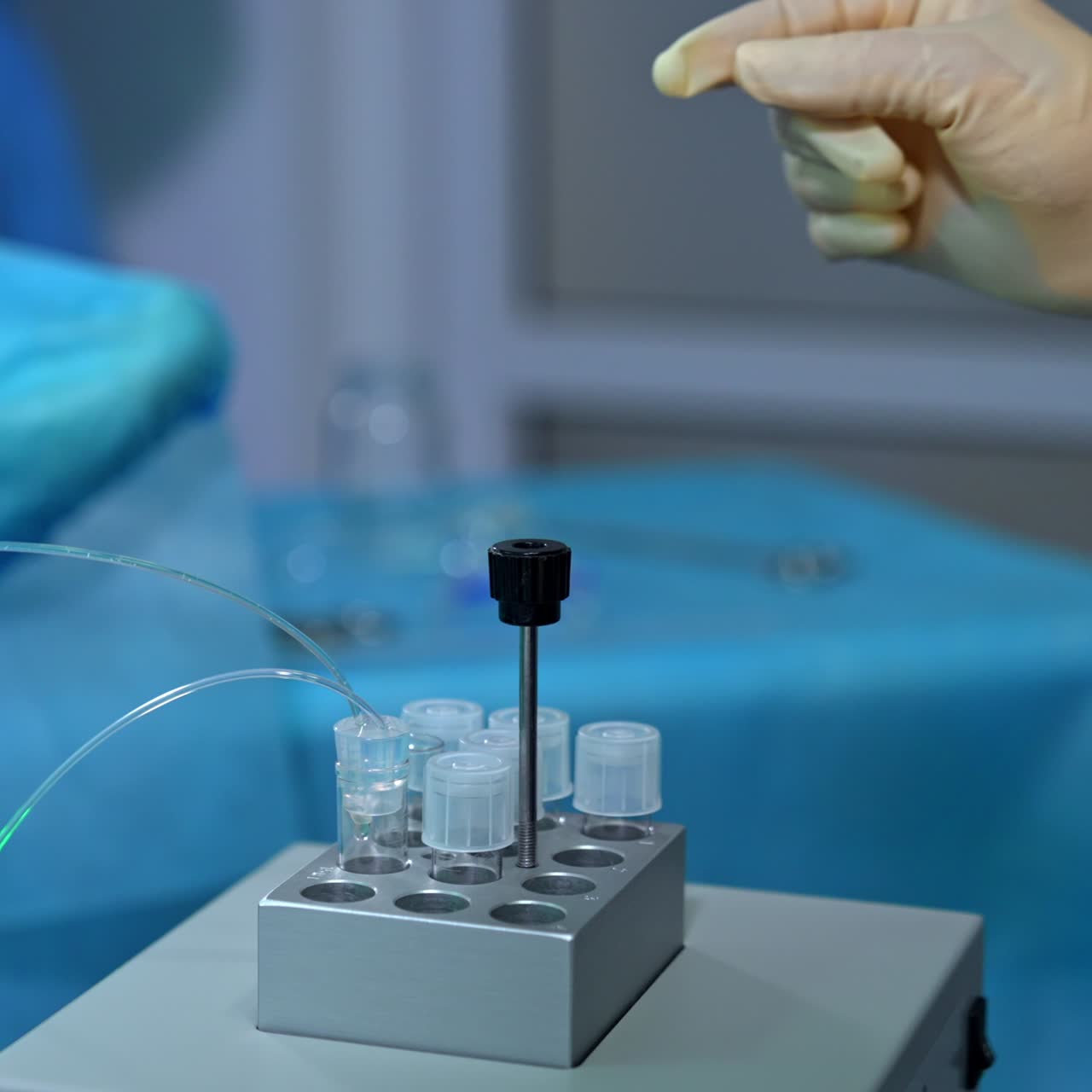 Equipment for extracorporeal fertilization procedure in the modern clinics. Hand in latex glove closes the lid with tubes connected to it