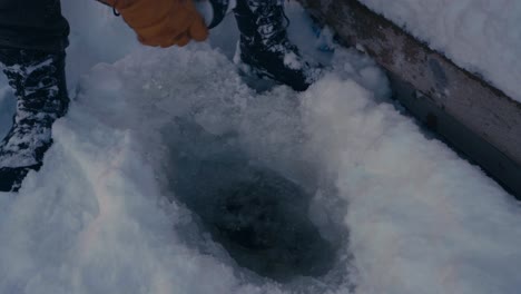 el hombre está llenando un vaso térmico con agua de lago congelada