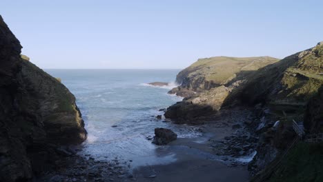 olas rompiendo la bahía junto al castillo de tintagel en cornualles, inglaterra