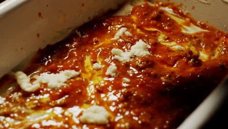 sprinkling mozzarella cheese above of bolognese sauce, making lasagna recipe