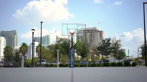 looking down downtown basketball court with urban cityscape skyscrapers and cranes in business district background