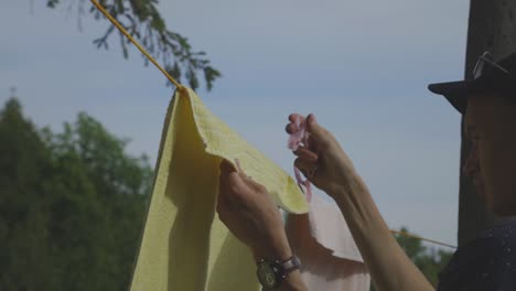 Man-Removing-Clothespins-And-Dry-Towel-From-The-Clothesline-Outdoor---close-up-slowmo