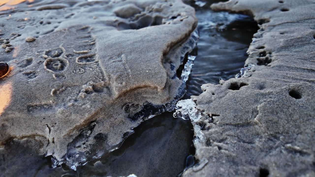 The water current flowing down the slope washed away the sand, carving a channel that led into the sea. Scandinavia Denmark.