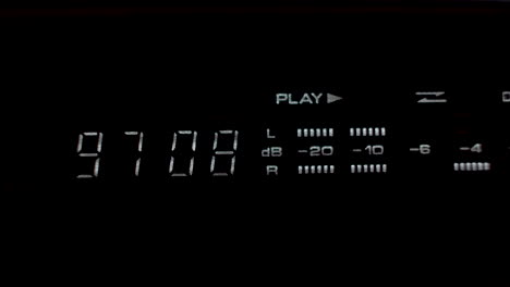 A close up shot of a digital display unit of a tape deck stereo system, the display providing a time metre and decibel reading as music is played from an old cassette