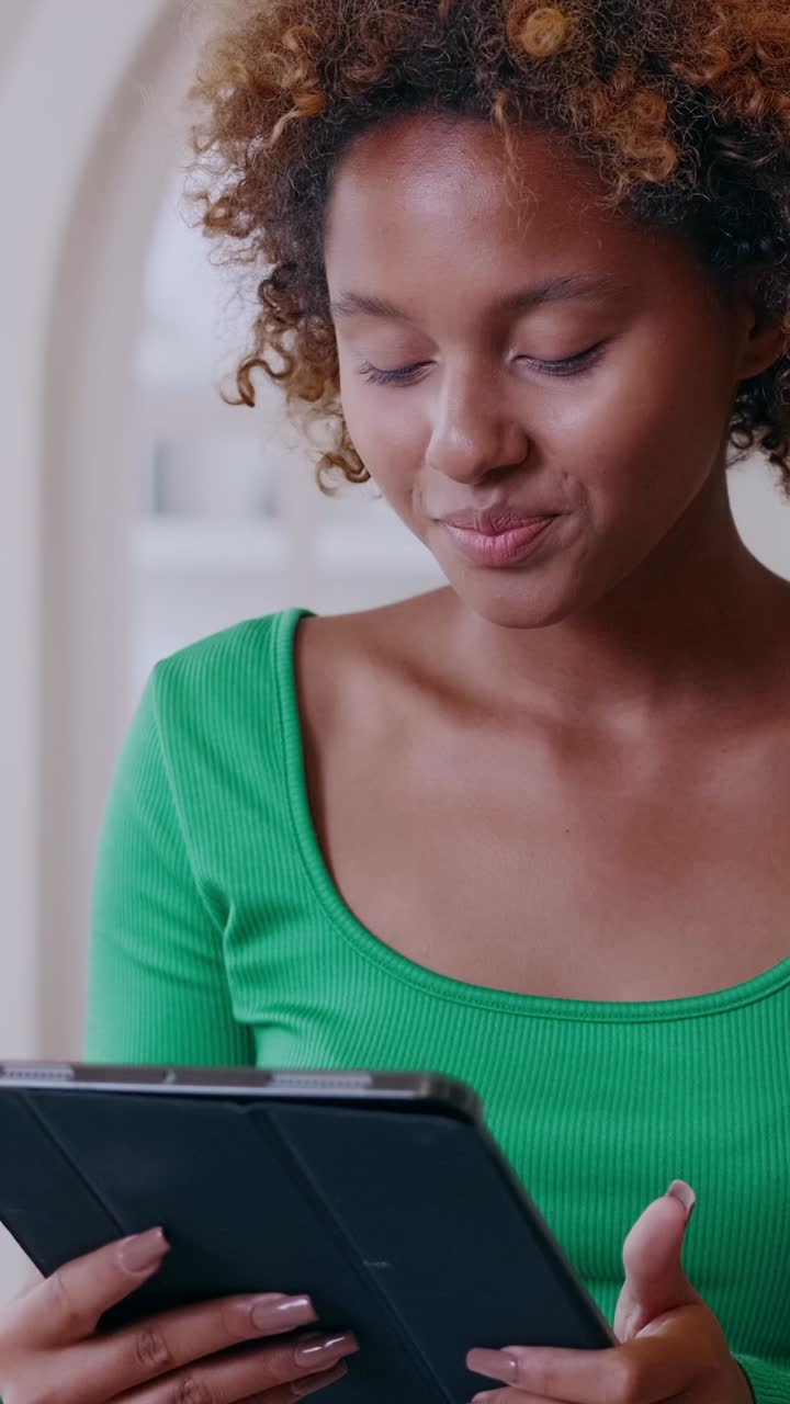 Young woman using tablet in home office smiling and scrolling through content