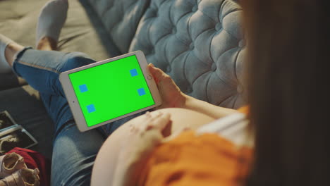 mujer embarazada usando una tableta con pantalla verde