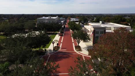 Aerial-dolly-push-in-above-trees-as-American-flag-waves-in-wind-at-start-of-downtown-historic-Clermont-Florida