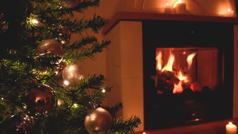 beautiful christmas tree with silvery decoration and soft white lights near a peaceful fireplace with candles