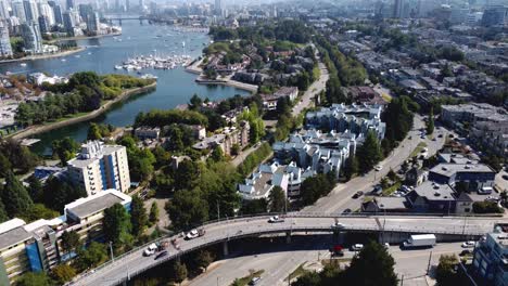 aerial hold dolly roll over false creek granville island waterfront residential condominium apartment townhouse homes parked yachts sail boats parks forests luxury towers modern architecture bridges