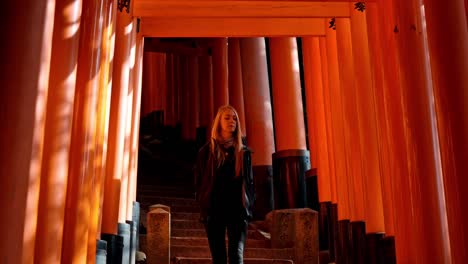 a woman gracefully walks down the stone steps of fushimi inari shrine in kyoto, japan, surrounded by countless vermilion torii gates.