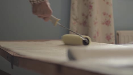 man decorator using roller to apply adhesive paste on roll of wallpaper-1