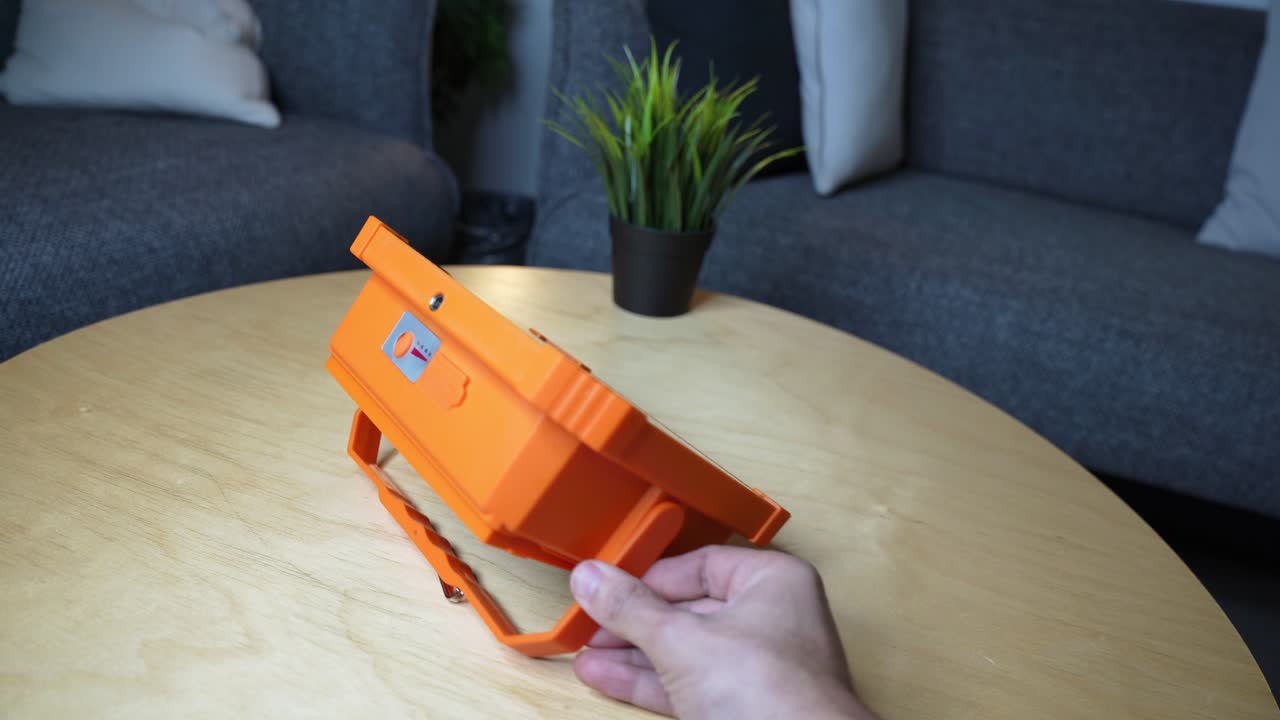 Close-up of a bright orange LED floodlight being positioned—ideal for product showcases, lighting demos, or tech explainer content.