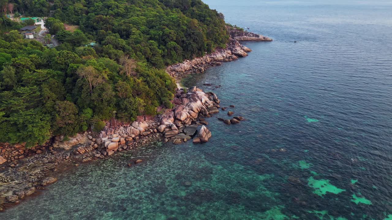 Capturing the beauty of a tropical island, turquoise waters and rocky coastline, this aerial view shows vibrant blue and green hues against rugged cliffs and shores