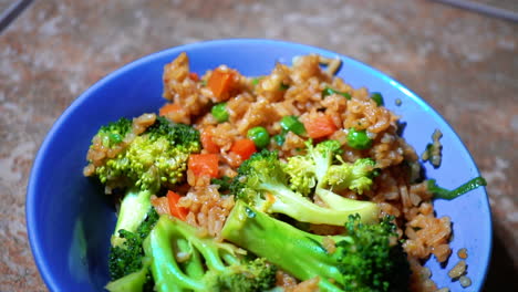 closeup of stir fried rice with broccoli and vegetables in blue bowl