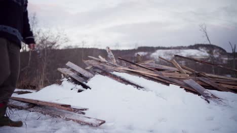 The-Man-is-Stacking-the-Wooden-Planks-in-the-Snow-in-Indre-Fosen,-Trondelag-County,-Norway---Static-Shot