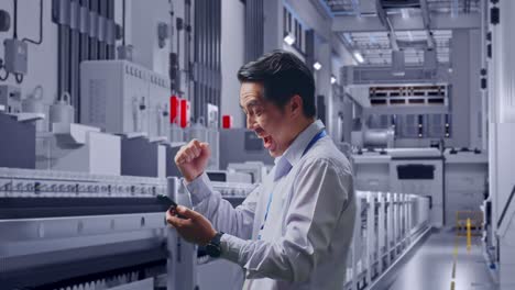 side view of an asian male professional worker with his smartphone at pharmaceutical factory, vaccine production facility, he raises his fist up with screaming goal after check on the smartphone