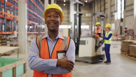 Portrait-of-african-american-male-worker-wearing-safety-suit-and-smiling-in-warehouse