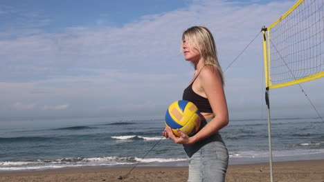 Fröhliches,-Sportliches-Mädchen-Mit-Ball,-Das-Am-Strand-In-Die-Kamera-Schaut.