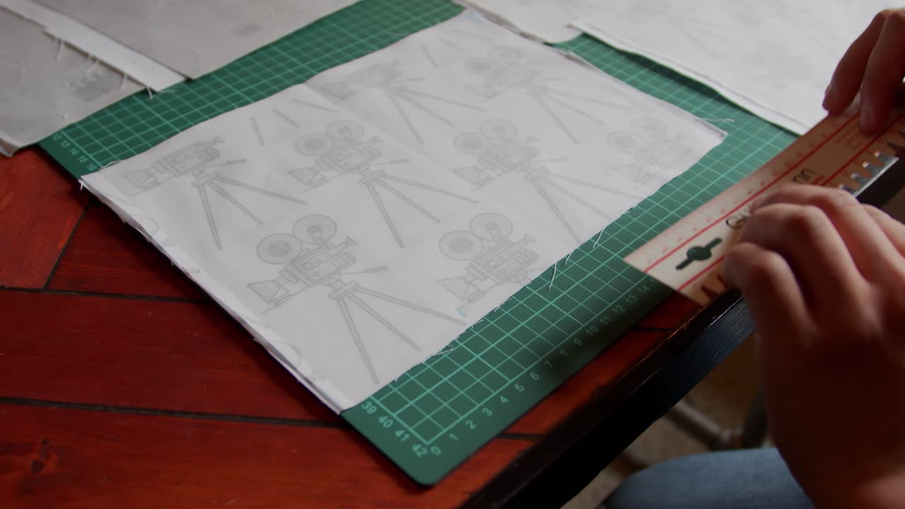 Hands making a mark on fabric using ruler to measure. Slow motion.