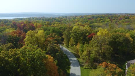 Aerial-Establishing-Shot-of-Private-Suburban-Neighborhood-Hidden-between-Colorful-Trees-in-Autumn