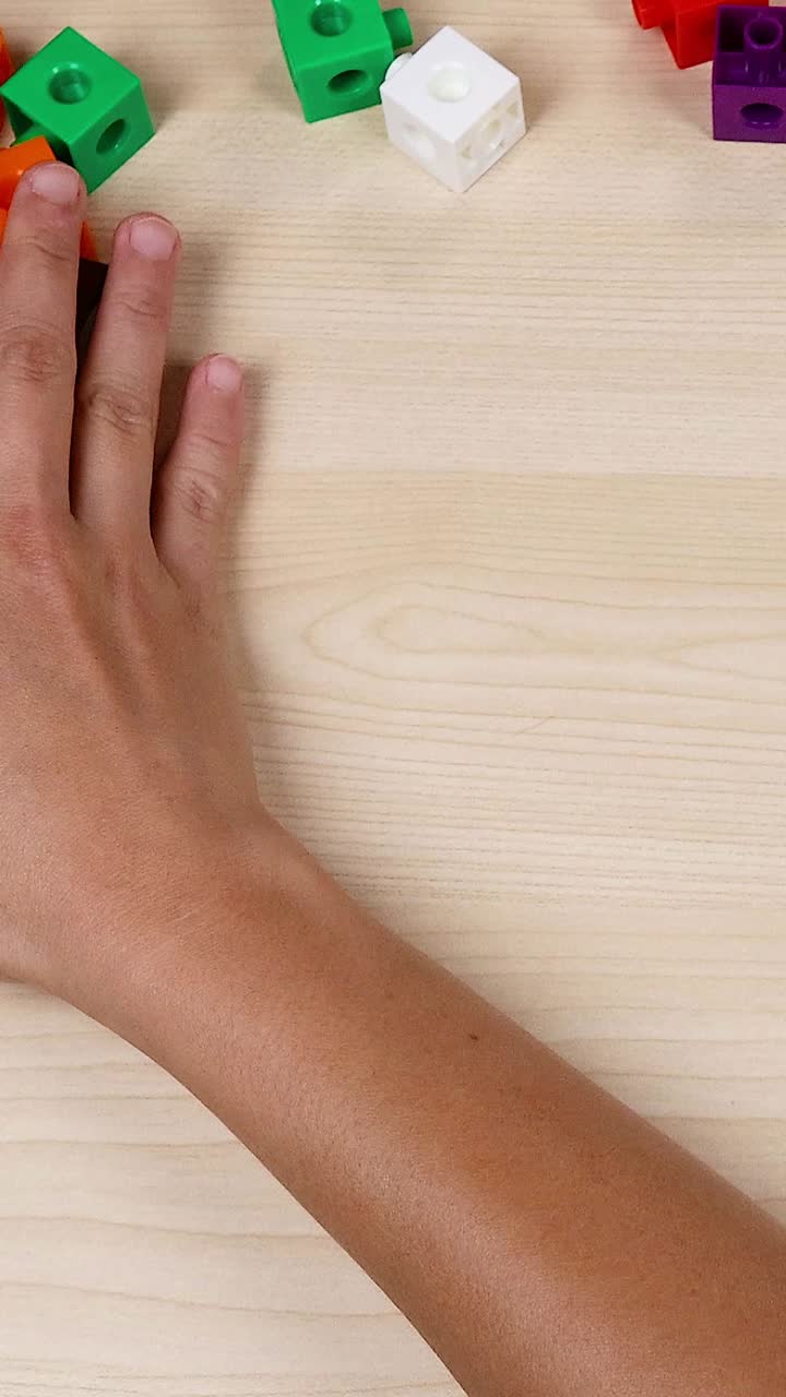 las manos organizan cubos coloridos en una mesa de madera