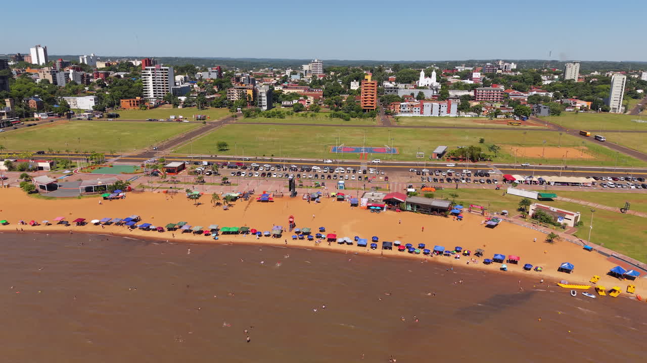 Experience an aerial view of Encarnacion, Paraguay, as beachgoers and tourists enjoy a sunny day out at Playa San Jose.