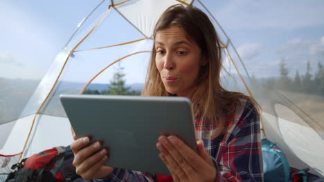 mujer haciendo una llamada de video en una tableta en una tienda de campamento