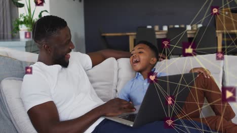 Animation-of-network-of-connections-over-happy-african-american-father-and-son-using-laptop