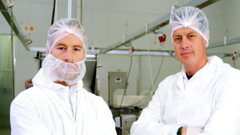 two butchers standing in meat shop with arms crossed