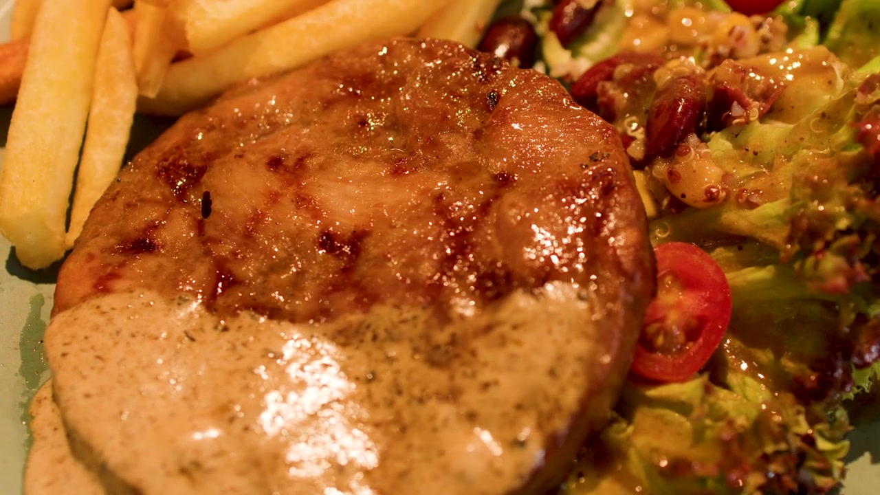 Primo piano di una bistecca alla griglia condita con salsa cremosa ai funghi e insalata di contorno.