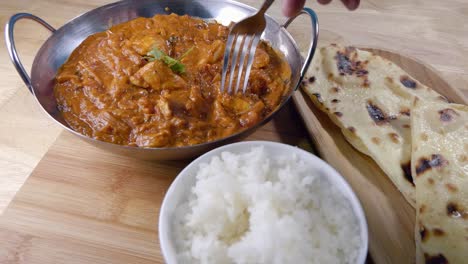 slider shot of eating an homemade indian curry in a balti dish with rice and butter naan bread