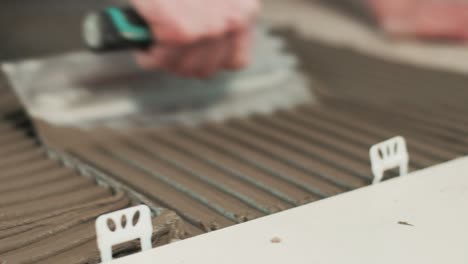 Construction-worker-spreading-tile-adhesive-on-the-floor