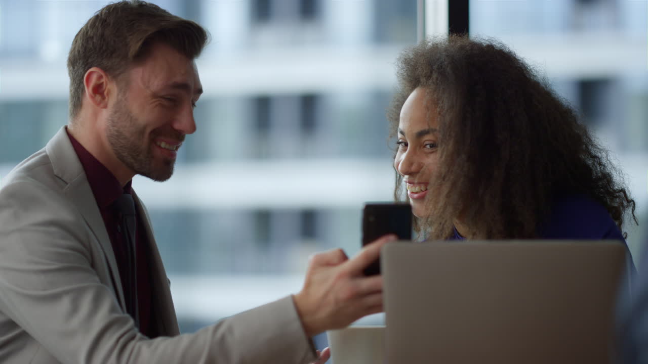 diversos gerentes de equipo trabajando juntos leyendo buenas noticias en el teléfono móvil en un café