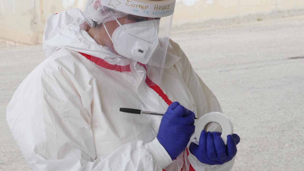 A medical worker in full protective gear writes labels for coronavirus testing kits during the COVID-19 pandemic at Stelios Kyriakides Stadium in Paphos, Cyprus.