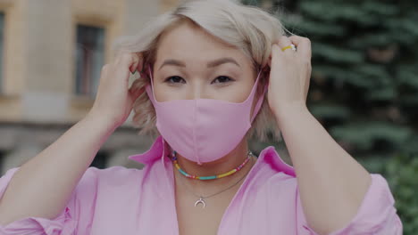 woman adjusting pink face mask