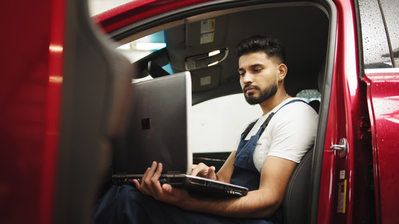 mecánico de automóviles trabajando en una computadora portátil en un coche