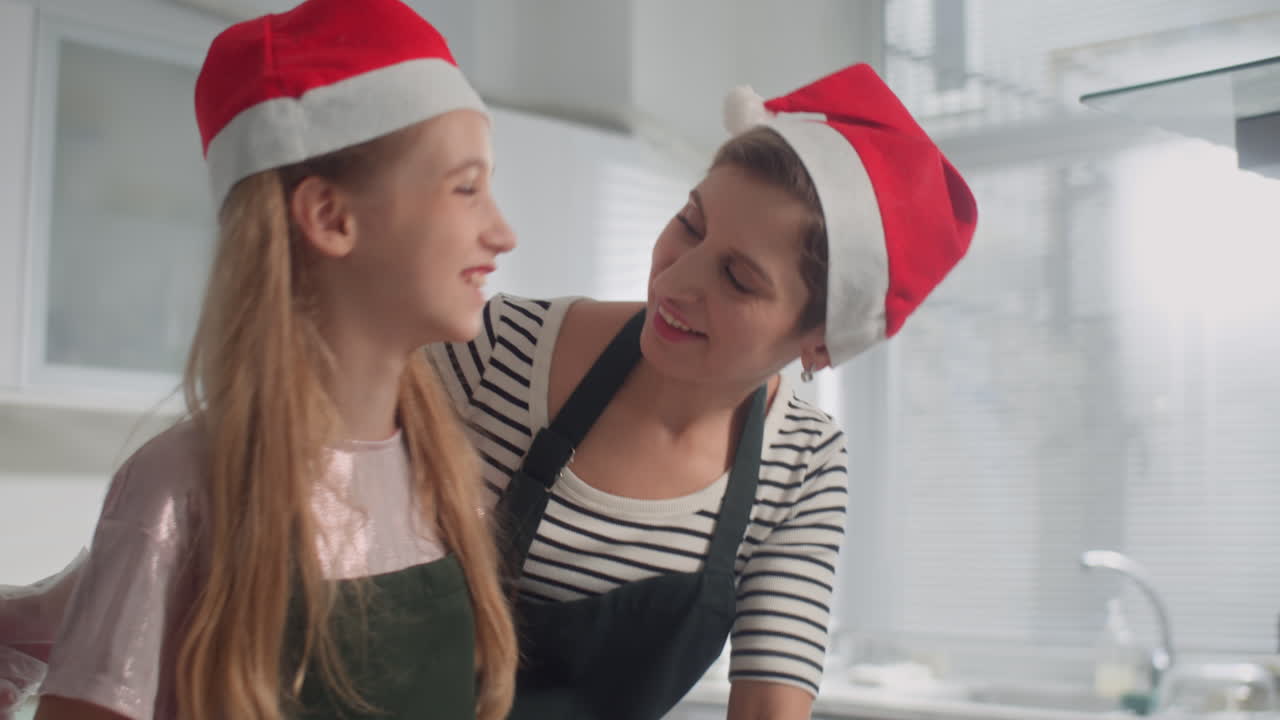 Mother and Daughter in Christmas Hats Kneading Chocolate Dough