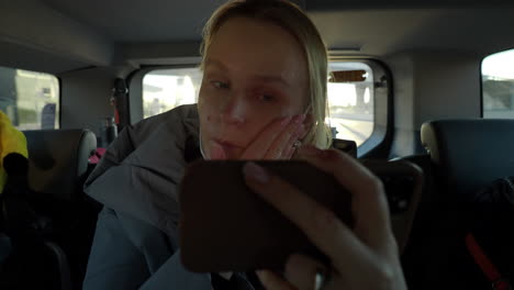 Woman applying make-up foundation in the car