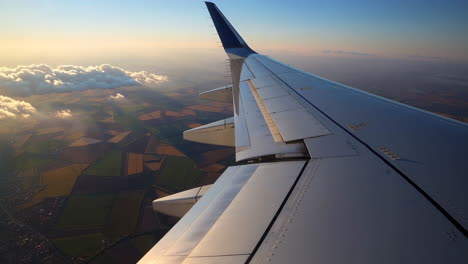 airplane wing view of clouds and farmlands