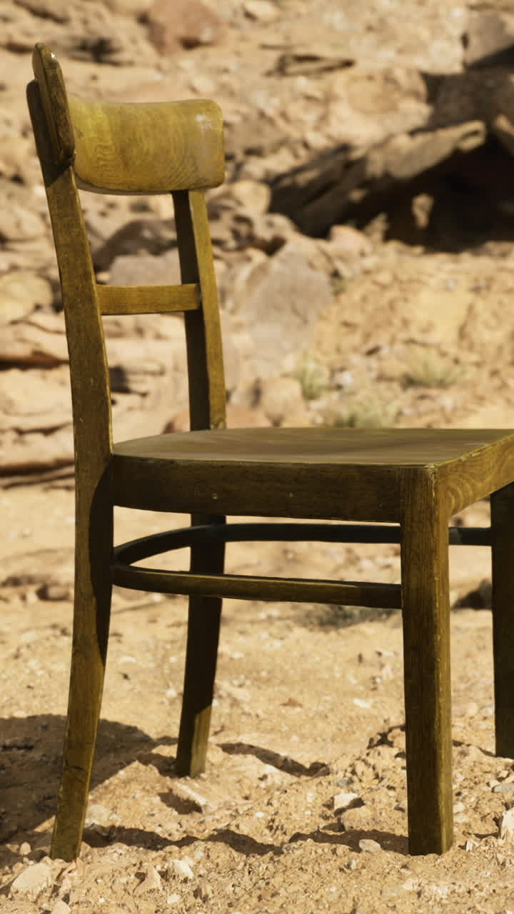 Empty wooden chair standing alone on arid terrain under bright sunlight