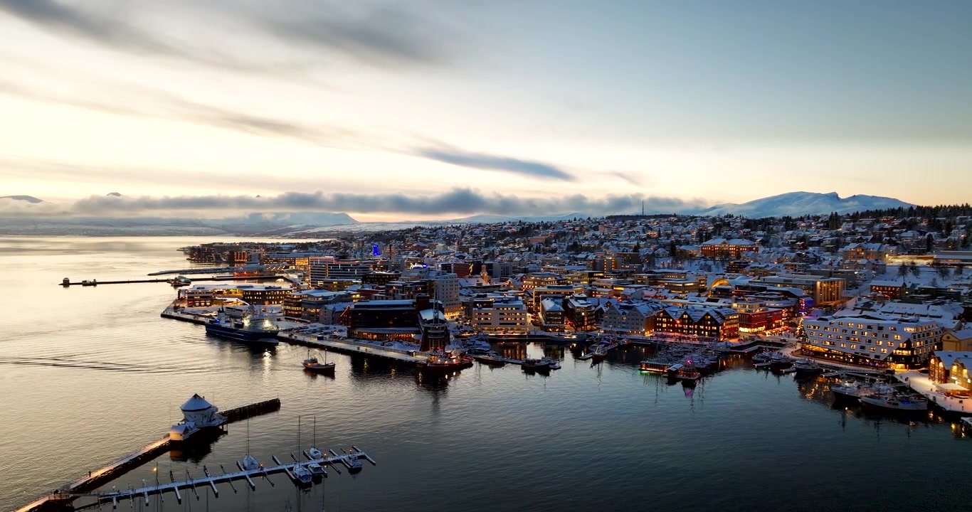 Tromsø, Norvège à l'heure bleue avec port illuminé, front de mer et paysage urbain enneigé. Idéal pour les concepts de voyage, d'hiver et de destination, vue aérienne cinématographique