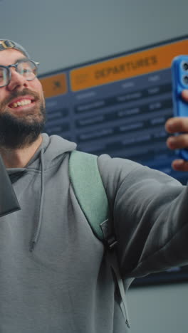 hombre en el aeropuerto tomando una selfie con tarjeta de embarque