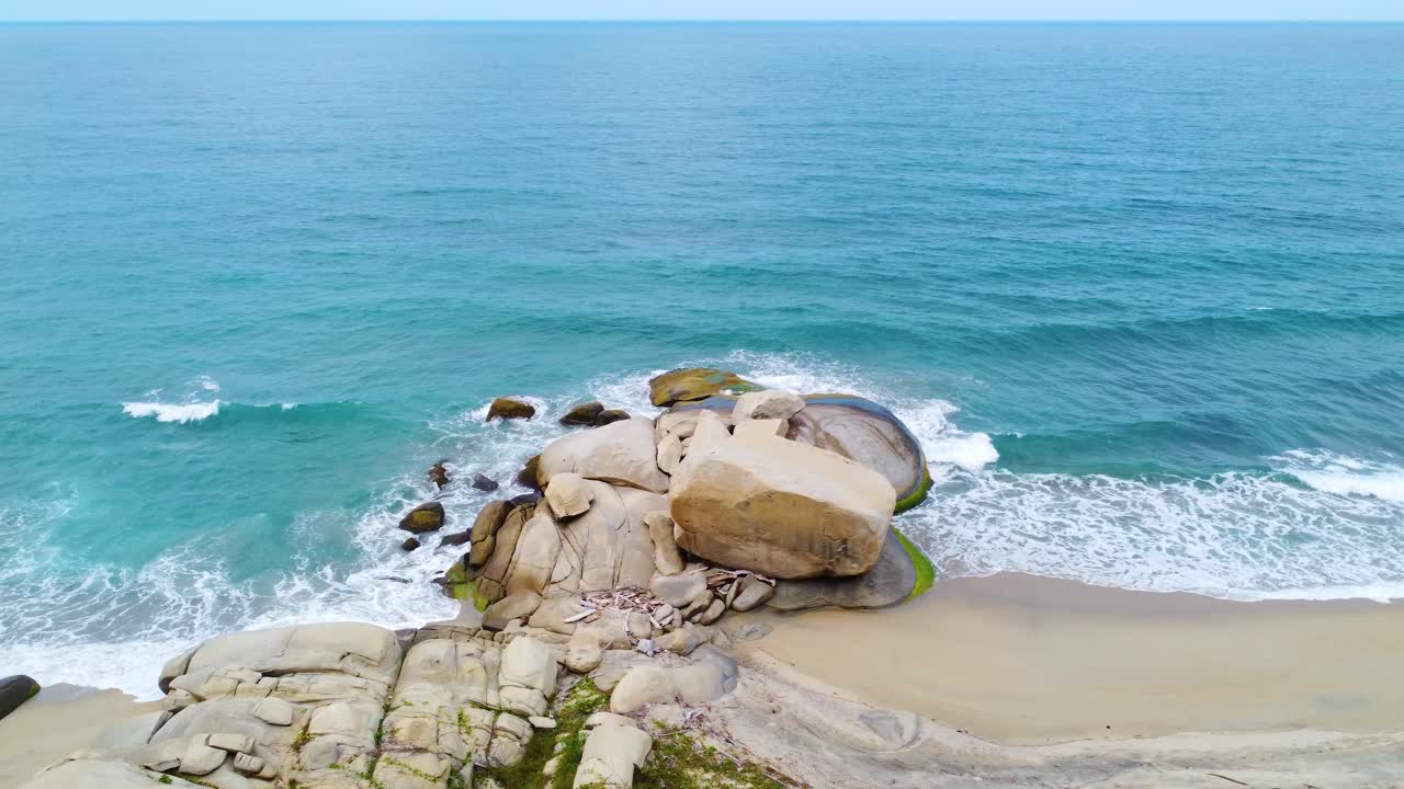 작은 조용한 파도가 해안선과 주변 바위에 부히는 해변을 따라 추적하는 드론, 콜롬비아