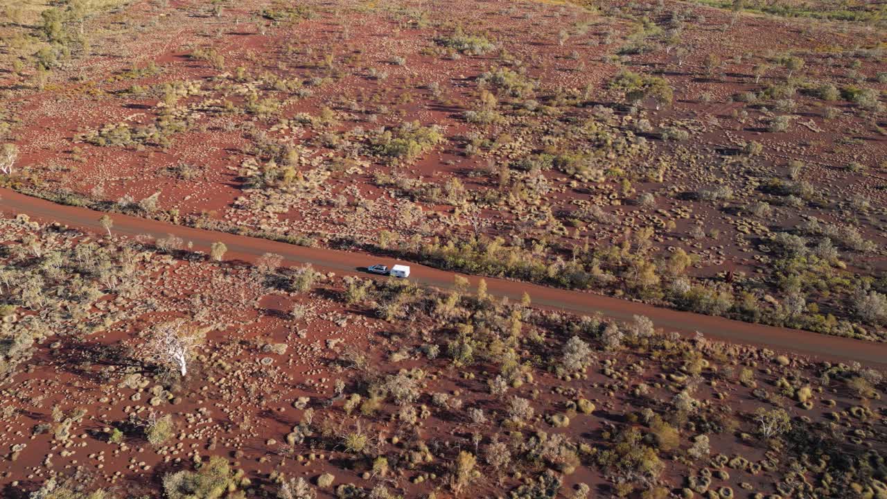 fotografía aérea de un remolque de camioneta conduciendo en una carretera del desierto durante la puesta de sol en el parque nacional de karagini, australia